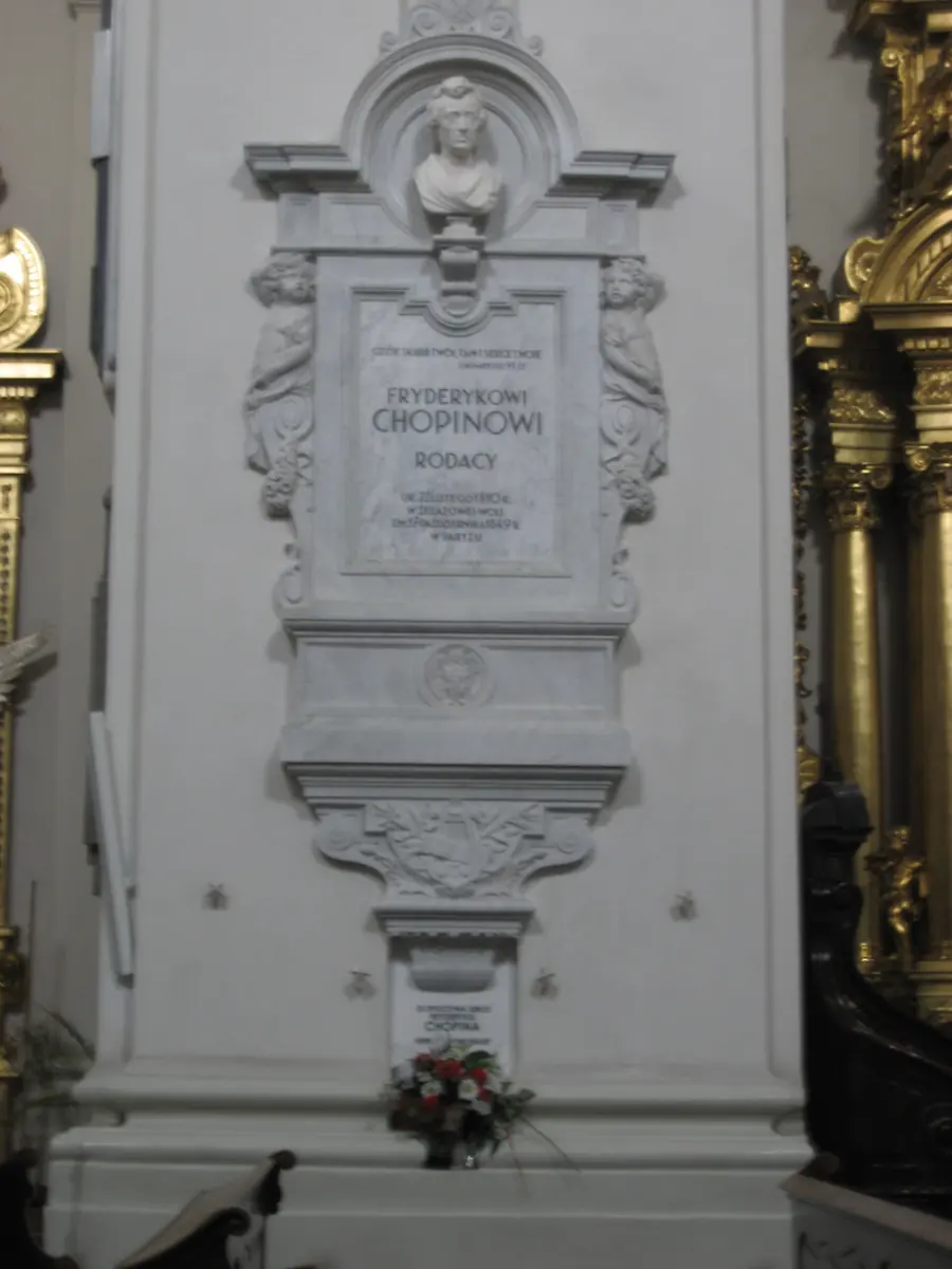 The white marble memorial on the pillar in Holy Cross Church where Chopin's heart is kept, with a bust of the composer above a Polish inscription.