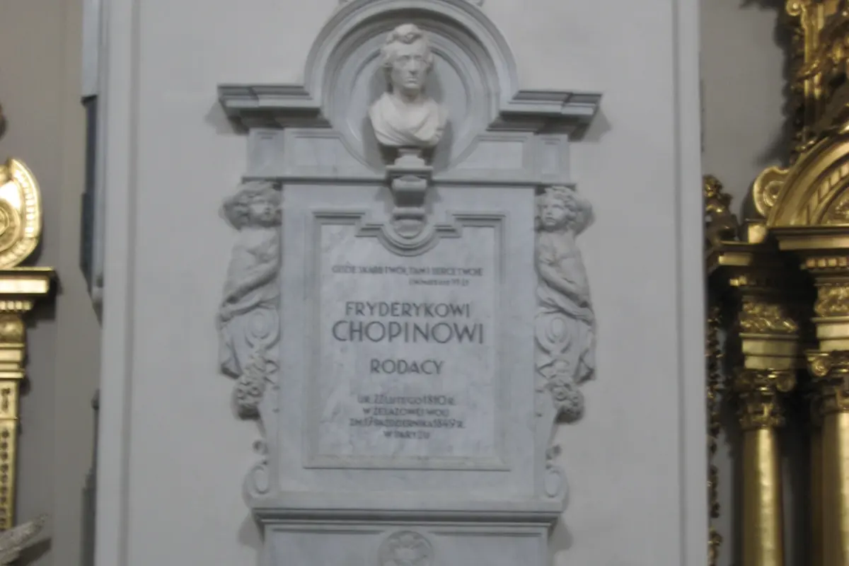The white marble memorial on the pillar in Holy Cross Church where Chopin's heart is kept, with a bust of the composer above a Polish inscription.