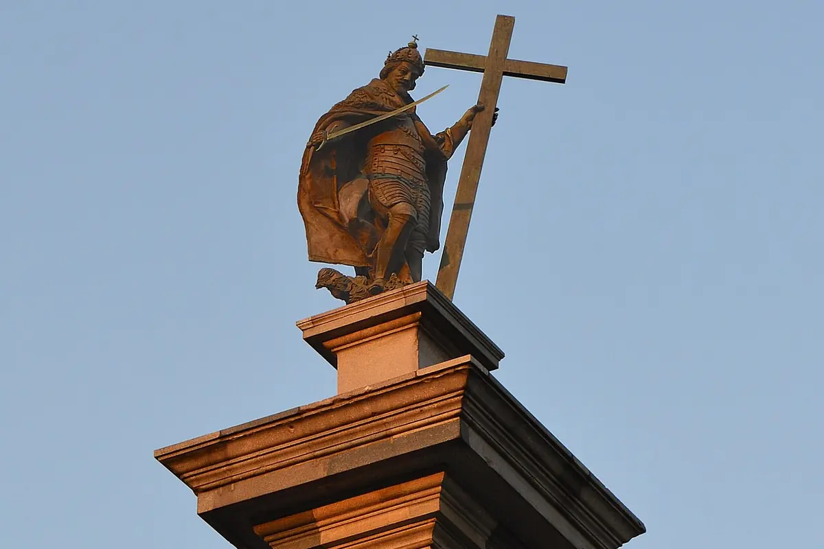 The bronze statue on top of Sigismund's Column in Warsaw, lit by warm evening sun.